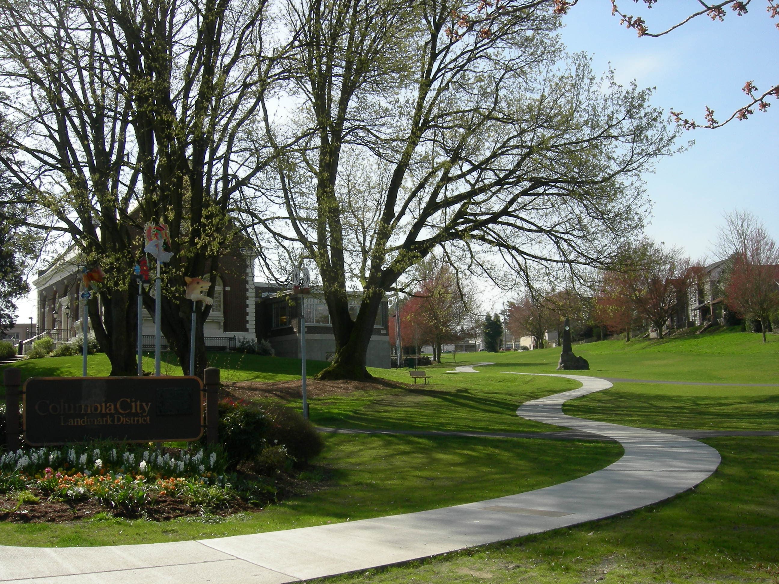 The Columbia City Landmark District sign and Carnegie library, with the village green in the foreground